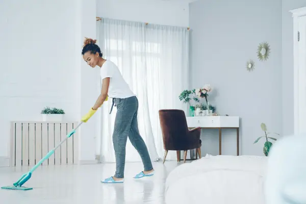 House cleaner mopping a bright living room floor
